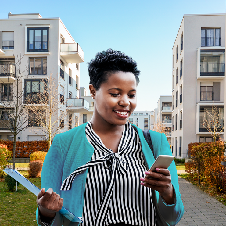 Woman in teal jacket and striped blouse looking at phone