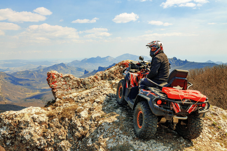 Man sitting on ATV on cliff